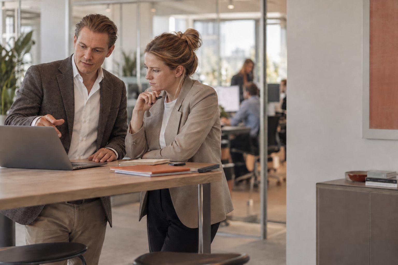 Two colleagues at a standing desk going through numbers on a laptop
